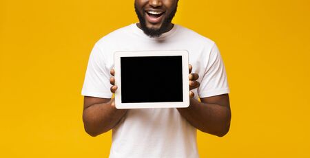Mockup for app. Blank digital tablet screen in black mans hands over yellow background, panorama with free spaceの写真素材