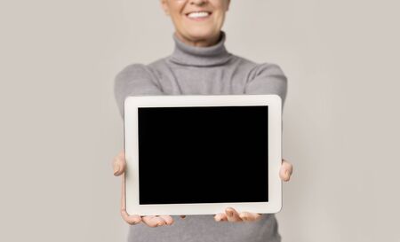 Digital tablet with blank screen in hands of senior woman, selective focus on device, free spaceの写真素材