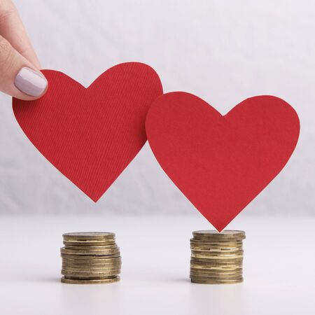 Wedding budget planning concept. Close up of two hearts with coins
