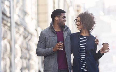 Couple date. Black man and woman drinking coffee outdoors, walking in the city, copy space