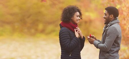 Love and relationship concept. Romantic man proposing to woman in autumn park, free space