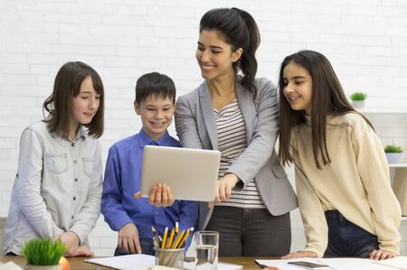 School kids with teacher looking on tablet computer in classroom, learning conceptの写真素材
