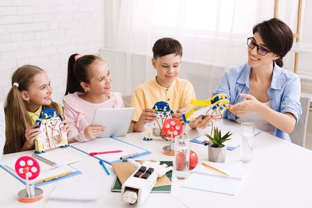 Children creating robots with teacher in classroom at stem lesson, woman showing handmade robotの写真素材