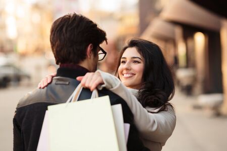 Successful shopping. Excited woman embracing husband, carrying shopping bags