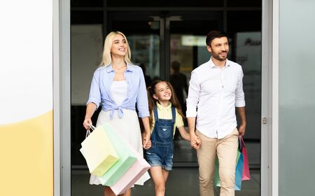 Seasonal Sales And Shopping. Happy Family Leaving Mall Center Carrying Shopper Bags. Free Spaceの写真素材