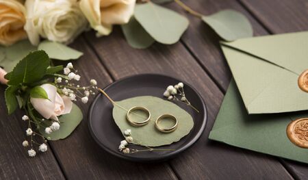 Creative Wedding rings composition on small plate on wooden background with stylish envelopes, panoramaの写真素材