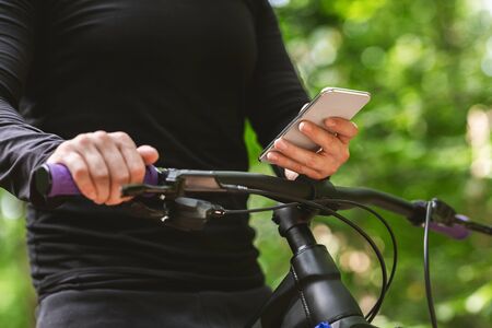 Tracking application. Male bicyclist using mobile app during open air sport activity, holding smartphone, free spaceの写真素材
