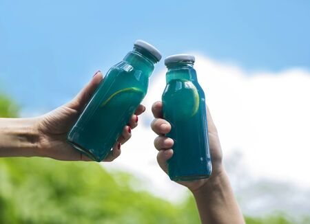 Blue Isotonic drinks for refreshing in summer in woman hands outdoor