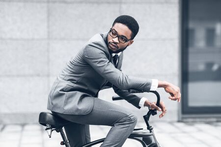 Way to work. Afro businessman riding bicycle to work in morningの写真素材