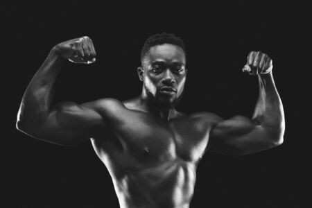 Professional african american bodybuilder demonstrating his muscular body, black and white photoの写真素材