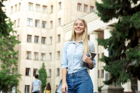 Happy girl resting between classes near university, smiling to camera outdoors, copy spaceの写真素材
