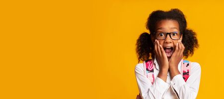Scared African American Schoolgirl Shouting With Fear Over Yellow Background In Studio. Panorama,...