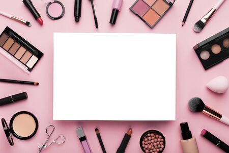 Girlish stuff. White blank sheet of paper surrounded by luxury decorative cosmetics on pinkの写真素材