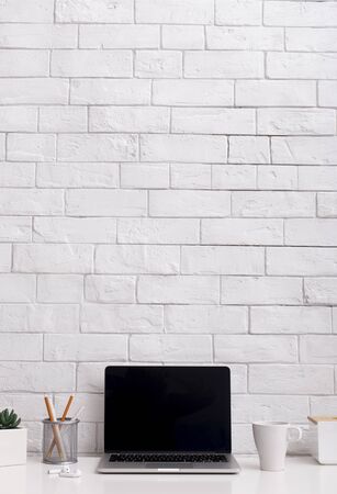 Minimalism concept. Office table with compact laptop with black blank screen on whiteの写真素材