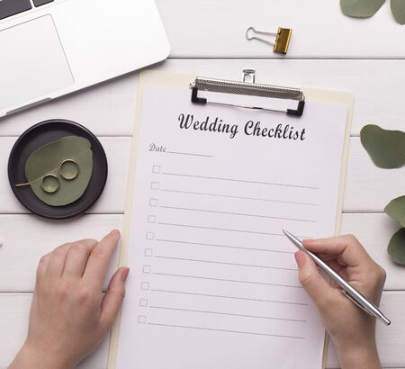 Woman writing wedding checklist on workplace at homeの写真素材