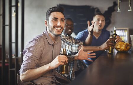 Mixed Race Football Fans Watching Match In Bar And Drinking Beer, celebrating victory, panorama with copy spaceの写真素材
