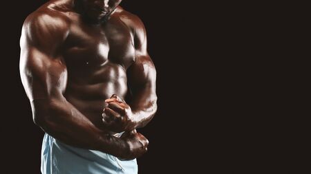 Strong biceps and chest of african bodybuilder, cropped, panorama with copy space, black backgroundの写真素材