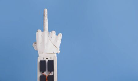 Independence of artificial intelligence. Robot hand show middle finger on blue background, free...