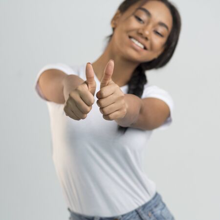 Overjoyed asian girl showing thumbs up and widely smiling, grey studio background, cropの写真素材