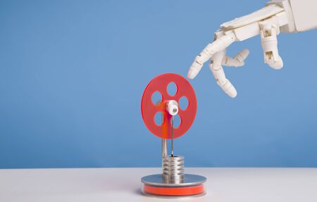 Industry 4.0 concept. Robot hand touching red plastic gear, blue background with free space
