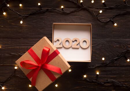 2020 New year concept in open gift box on wooden background with garland