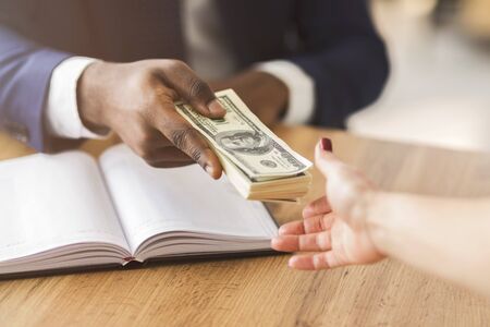 Corrupted unrecognizable african businessman sealing the deal, giving female partner venality bribe...
