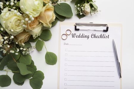Creative wedding planning checklist with roses and rings on white background, copy spaceの写真素材