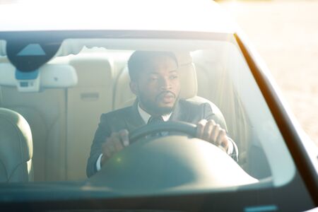 Serious businessman driving luxury car, view from the outside through the windshieldの写真素材
