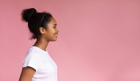 Profile portrait of beautiful african teenage girl looking at copy space on pink studio background, panoramaの写真素材