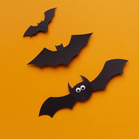Close up of funny Halloween bats flying up on orange background