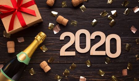 Happy New Year. Champagne, gifts and wooden 2020 concept on brown background, panorama