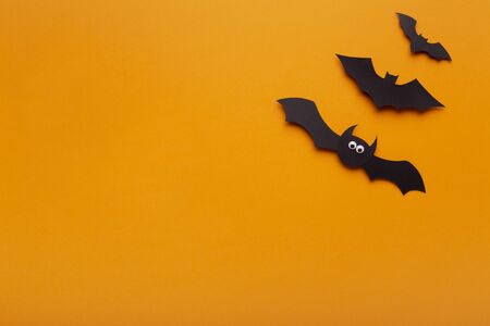 farewelling with Halloween. Black paper bats on orange background with copy space