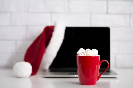 Happy Christmas holidays. Workplace with laptop and hot cocoa with marshmallow on office table