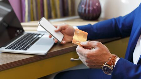 Easy payments. Hands of man holding credit card after online purchase and typing on mobile phone to...