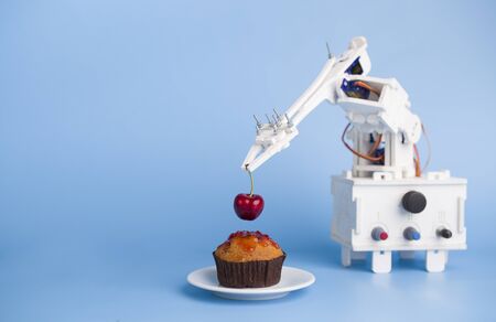 AI assistant preparing cupcake, helping with bakery cooking at kitchen, blue background with empty spaceの写真素材