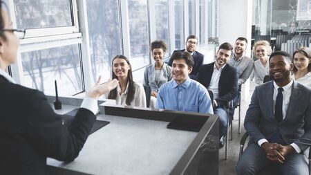 Young business team listening to speaker during group briefing negotiations in officeの写真素材