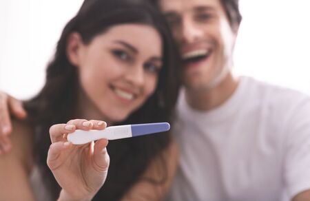 We gonna be parents! Happy couple showing pregnancy test on cameraの写真素材