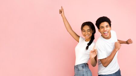 Joyful couple dancing and having good time over pink background, free spaceの写真素材