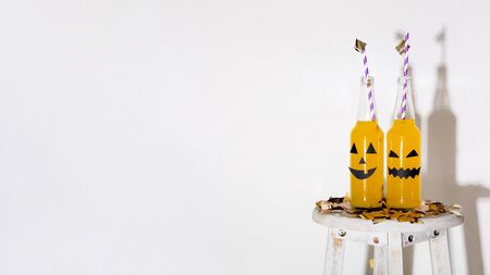 Halloween yellow drinks with drawing faces and straws on white background with shadow, panorama, copy spaceの写真素材