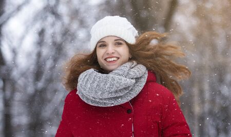 Young pretty girl with flying ginger hair enjoying winter day in park, copy space