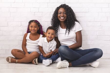 Single mother. Young african american woman with cute little kids, daughter and son, sitting on...