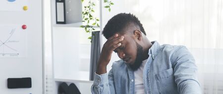 Hard work. Tired african american businessman suffering from migraine at workplace in office, panoramaの写真素材