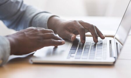 Hands of unrecognizable african american businessman typing on laptop keyboard in office, closeup with copy space, panoramaの写真素材