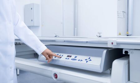 Doctor in medical gown starting X-ray machine in modern medical laboratory, copy space