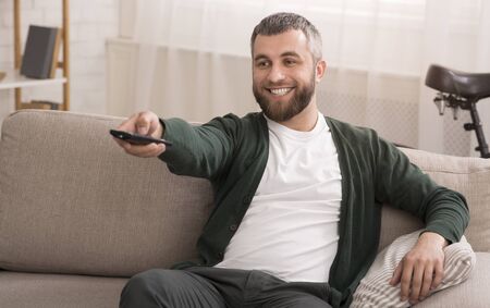 Middle aged cheerful man watching movies on tv at home, copy spaceの写真素材