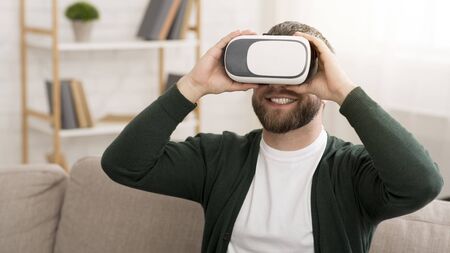 Bearded Middle Aged Cheerful Man Enjoying VR Glasses At Home, holding vr headset with both hands, copy spaceの写真素材