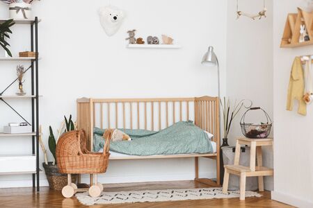 Baby Bedroom Interior with Cozy Wooden Bed, Wicker Stroller and Rack In Scandinavian Styleの写真素材