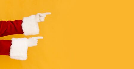 Santa Claus hands showing on copy space for promo or greetings on orange background, panoramaの写真素材
