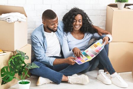 Married young african couple choosing walls colour for new apartment, watching colour sample setの写真素材