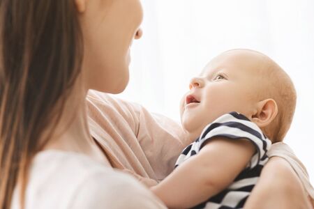 Cute newborn baby smiling while lying on mothers hands, closeup with free space